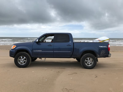 1stgenoffroad.com blue Toyota Tundra with lift on beach.